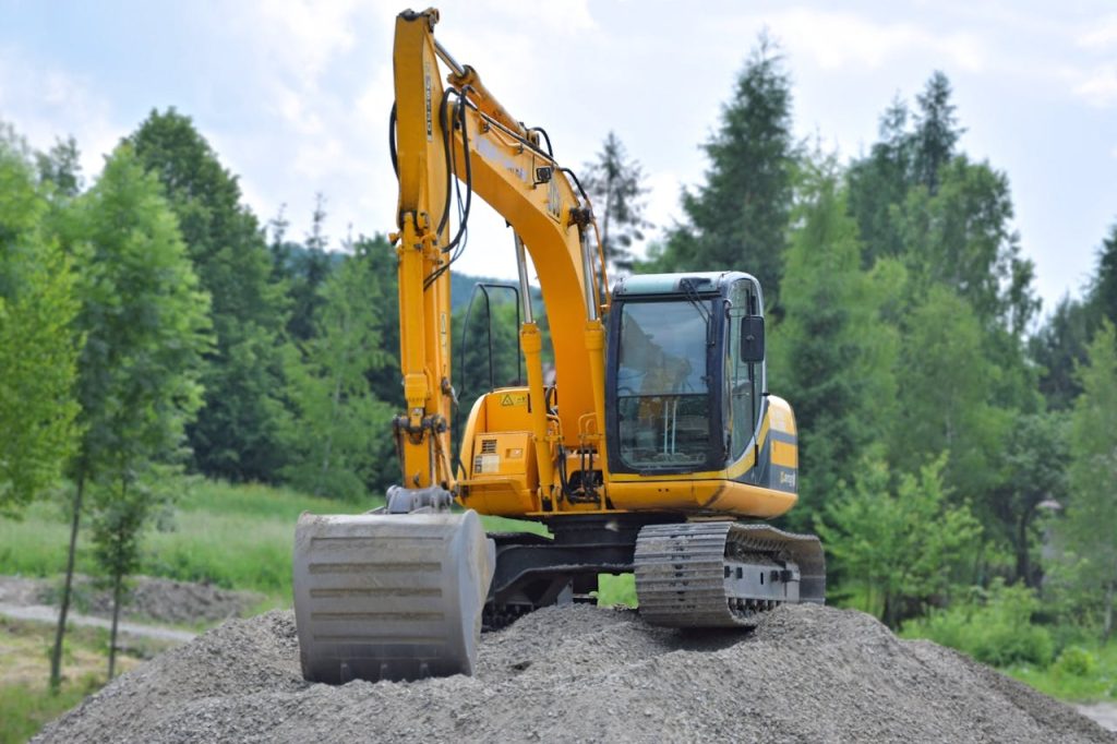 pexels-photo-95687 A yellow excavator on a pile of gravel in a lush, green forest setting in Poland.
